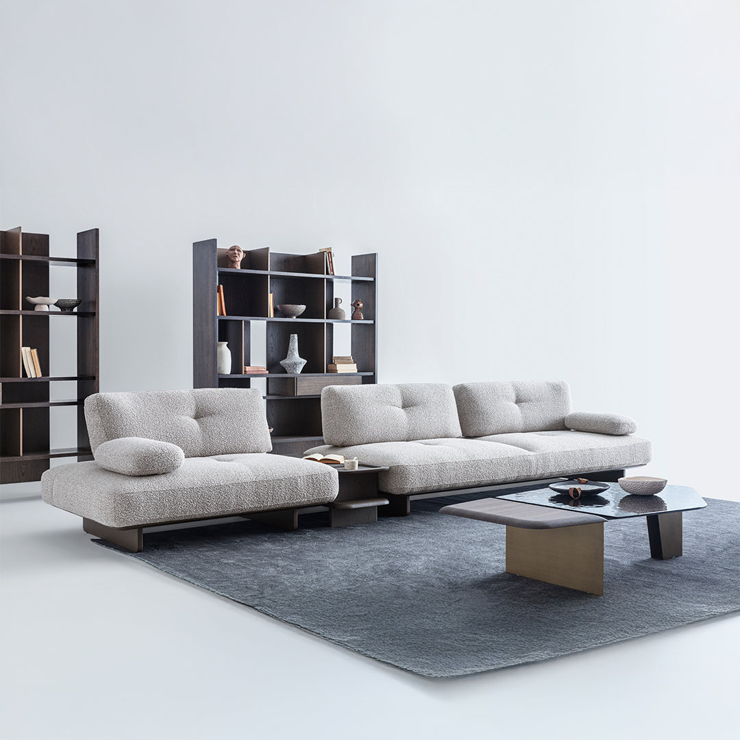 Modern living room with a gray sectional sofa, coffee table, and bookshelves.